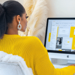 Black woman entrepreneur working at a desk designing systems on a computer, illustrating the content visibility trap and the shift toward building sustainable visibility systems that reduce burnout, replace daily posting pressure, and support long-term business growth.